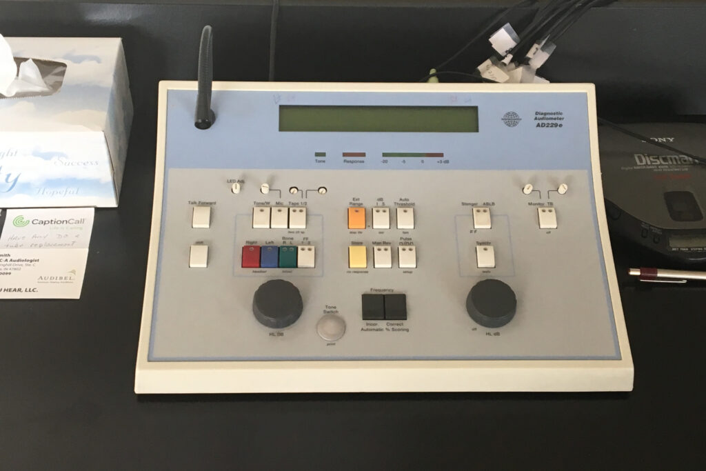 close-up of diagnostic audiometer on table next to box of tissues